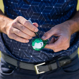 A person holds a golf ball with a green alignment tool in one hand and a black marker in the other, preparing to mark the ball.