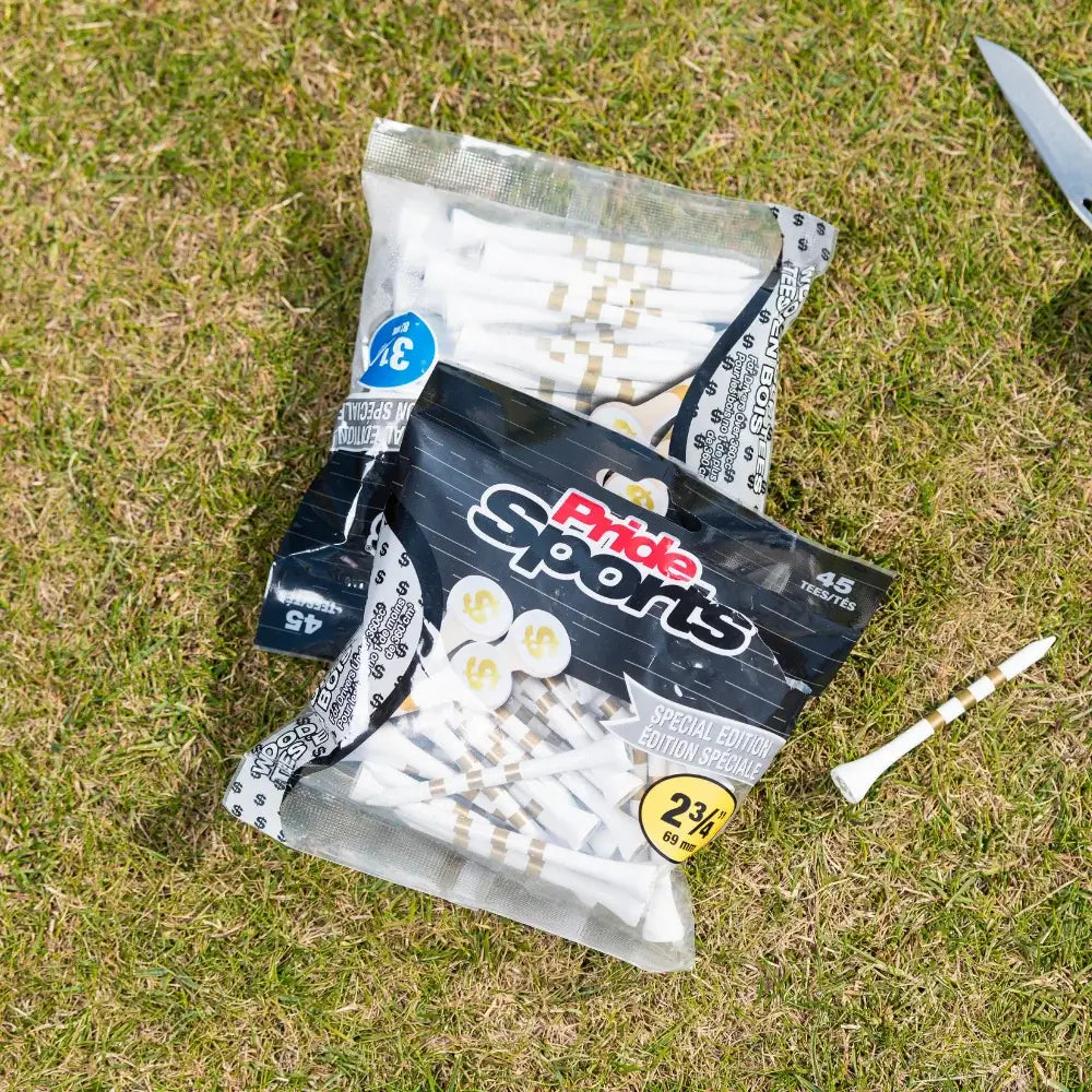 A bag of pride sports golf tees featuring a special edition dollar sign design and containing 45 tees, set on grass, with a few tees scattered nearby.