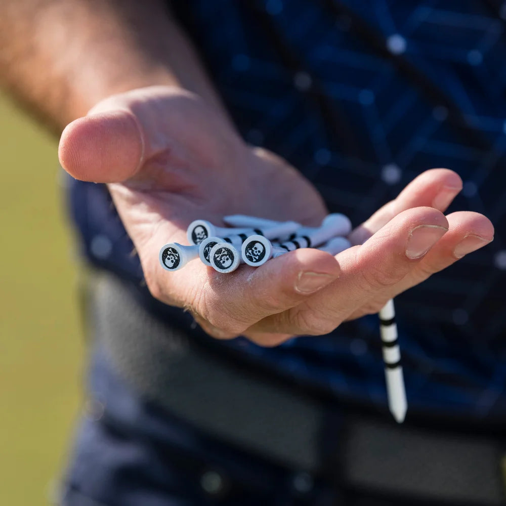 A person holding a couple of special edition skull and bones golf tees in their hand.