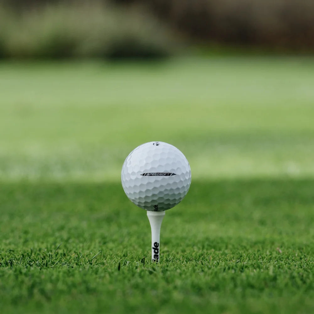 Golf ball on a tee in the grass with a blurred background