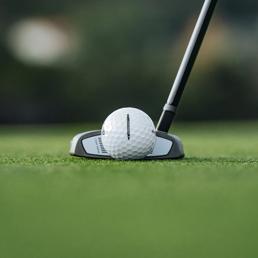 Golf ball and club on a green golf course