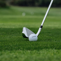 Golf club and ball on a green grass surface