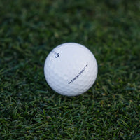 TaylorMade Tour Response golf ball resting in the grass at dusk.