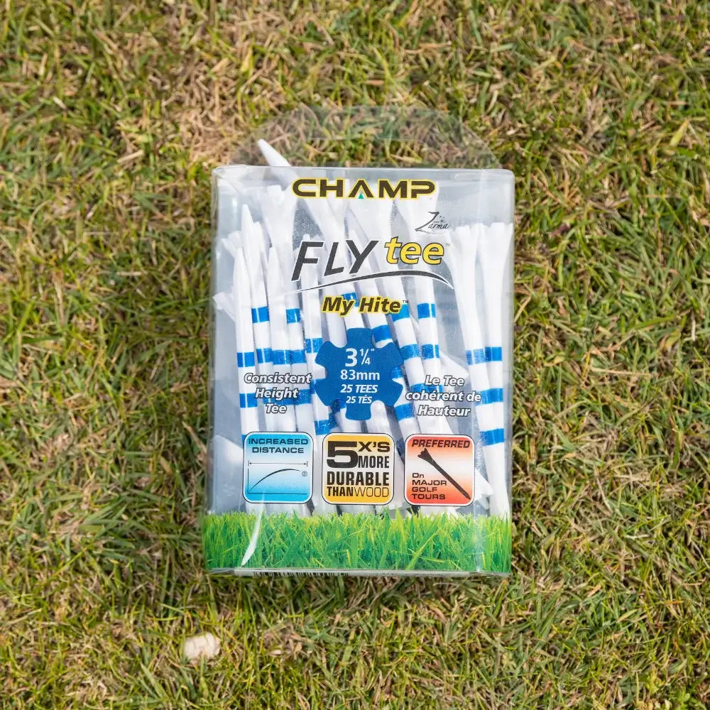 A package of white golf tees with blue stripes lying on grass, labeled "champ fly tee," containing 30 tees of 3¼ inches.